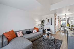 A grey sofa with orange and white pillows sits in a living room.