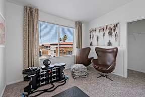 A room with a chair, a table, and a robotic vacuum cleaner.