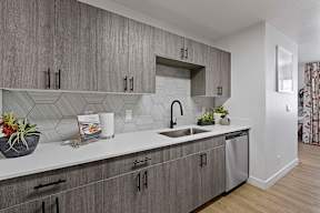 A kitchen with grey cabinets and a white counter top.