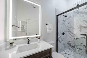 A bathroom with a marble shower and a white sink.