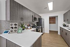 A modern kitchen with a white countertop and wooden cabinets.