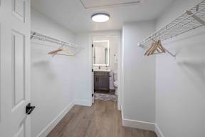 A hallway with a white door and a white wall with a wood floor.