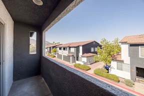 A balcony view of a residential area with houses and a car parked on the street.