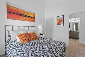 A bedroom with a large bed and a painting on the wall.
