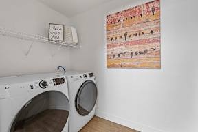 A laundry room with a washer and dryer and a painting on the wall.