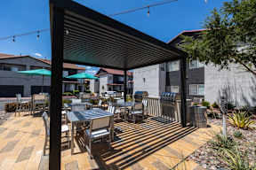 A patio with a table and chairs under a black awning.