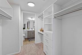 A white walk-in closet with shelves and drawers.