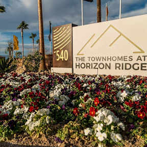 A sign for The Townhomes at Horizon Ridge is surrounded by flowers.