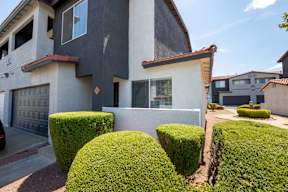 A house with a white garage door and a red trimmed window.