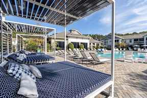 A patio with a blue mattress and a pool in the background.