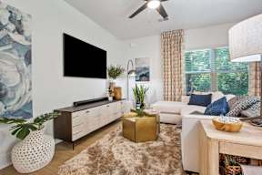 A living room with a white couch, a wooden coffee table, and a large painting on the wall.