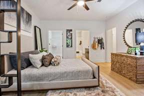 A bedroom with a bed, a dresser, and a mirror.