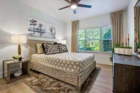 A bedroom with a bed, nightstand, and a painting on the wall.