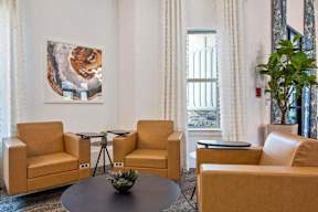 A living room with a painting on the wall and a plant on the side table.