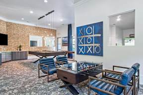 A room with a pool table and chairs.