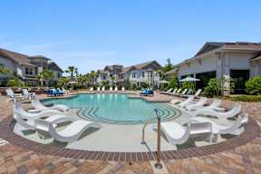 A swimming pool surrounded by white lounge chairs.