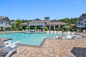 A large swimming pool surrounded by lounge chairs and umbrellas.