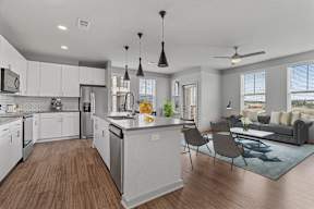 A modern kitchen with white cabinets and a wooden floor.