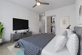 A bedroom with a bed, a television, and a ceiling fan.