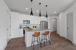 A kitchen with a white island and bar stools.