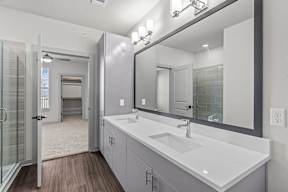 A bathroom with a sink, mirror, and a glass shower door.