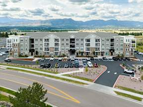 A large apartment complex with a parking lot in front.