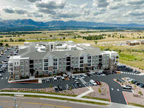 A large apartment complex with a parking lot in front.