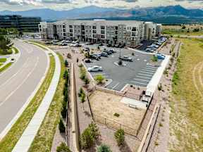 A parking lot in front of a large building with a mountain in the background.