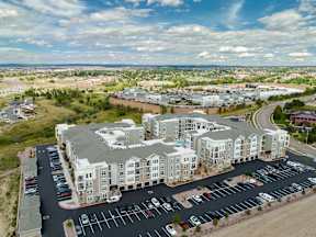 A large apartment complex with a parking lot in front.