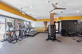 A gym with treadmills, exercise bikes, and a fan.