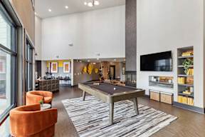 A living room with a pool table and a television.