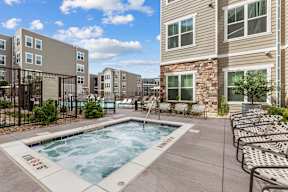 A swimming pool surrounded by lounge chairs and apartment buildings.