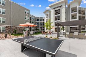 A table tennis table is in the middle of a courtyard with a building in the background.