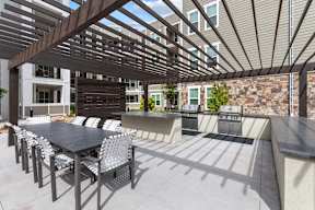 A patio with a table and chairs under a wooden pergola.