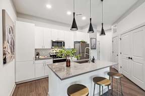 A kitchen with a white counter and bar stools.