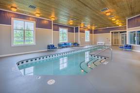 A large indoor swimming pool with a wooden ceiling and windows.