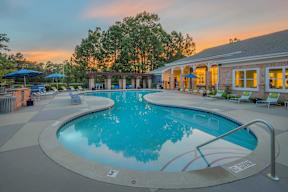 A large outdoor swimming pool with a sunset in the background.