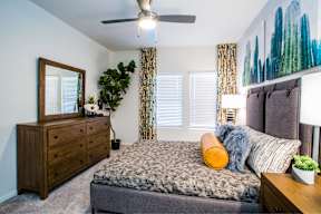 a bedroom with a bed and a dresser and a ceiling fan