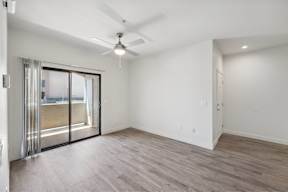 an empty living room with a sliding glass door to a patio