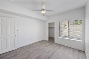 an empty living room with a ceiling fan and a large window