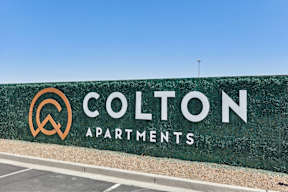 a green wall with the colton apartments logo on it