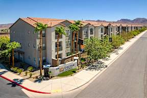 a row of apartment buildings with palm trees in front of a street