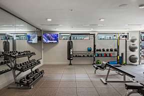 A gym with a variety of equipment including dumbbells, weight plates, and a bench press.
