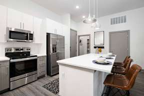 A modern kitchen with a white island and stainless steel appliances.