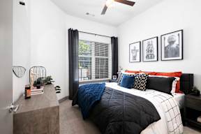 A bedroom with a bed, a nightstand, and a window with curtains.