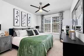 A bedroom with a bed, nightstand, and a ceiling fan.