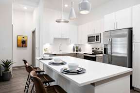 A modern kitchen with a white countertop and stainless steel appliances.