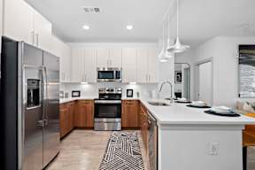 A modern kitchen with a refrigerator, oven, and sink.