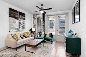 A living room with a beige couch, a coffee table, and a ceiling fan.