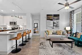 A modern kitchen with white cabinets and a bar area with stools.
